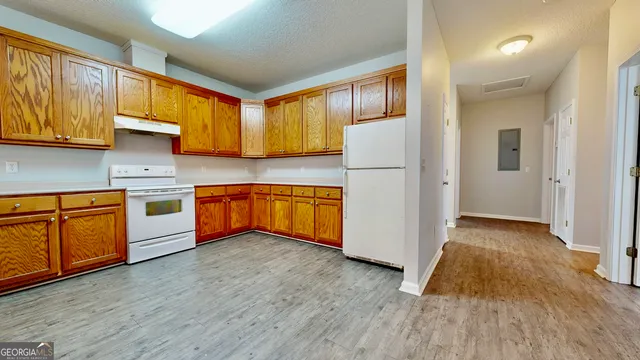 a kitchen with wooden floors and white stainless steel appliances