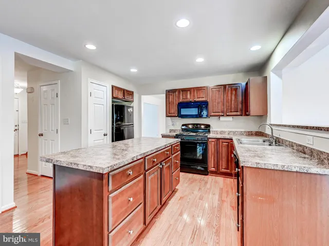 a room with stainless steel appliances kitchen island a table chairs in it and wooden floors