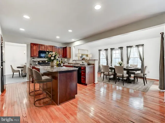 a open kitchen with stainless steel appliances granite countertop a refrigerator a stove top oven a sink dishwasher and white cabinets with wooden floor