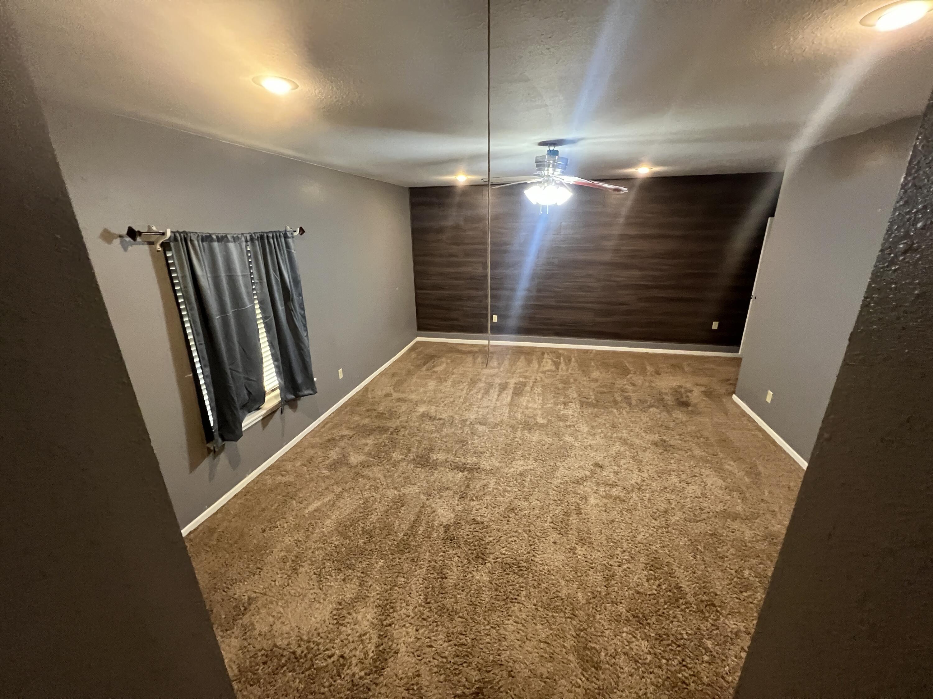 203 Northeast Alpine Plainview, TX 79072 - Photo 7 of 15 en empty room with stairs and wooden floor