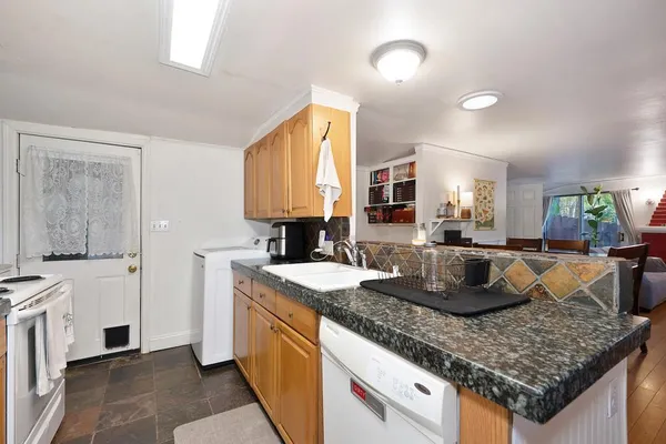 a kitchen with granite countertop kitchen island stainless steel appliances a sink stove and cabinets
