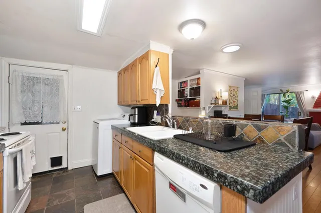 a kitchen with granite countertop kitchen island stainless steel appliances a sink stove and cabinets
