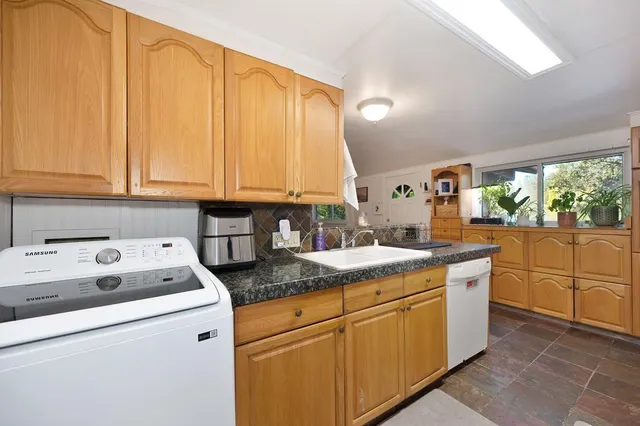 a kitchen with granite countertop cabinets sink and white appliances