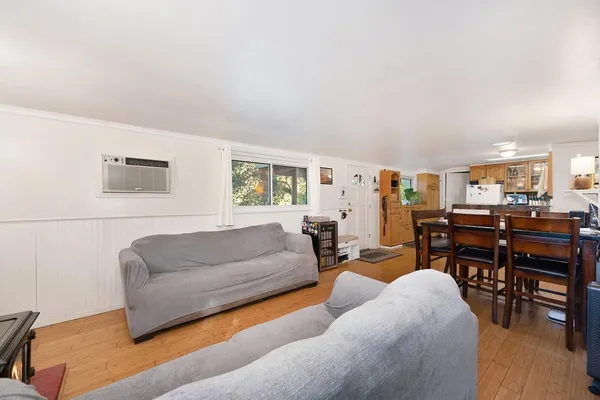 a living room with furniture and a dining table with wooden floor