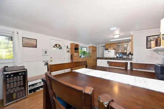 a room with stainless steel appliances kitchen island granite countertop a table chairs and a refrigerator