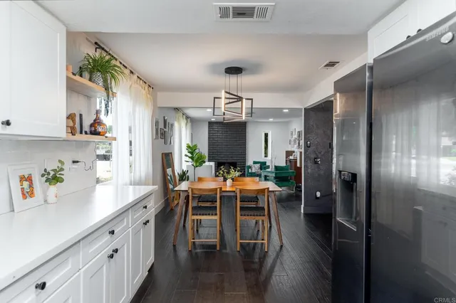 a kitchen with stainless steel appliances granite countertop a refrigerator a sink dishwasher a dining table and chairs with wooden floor