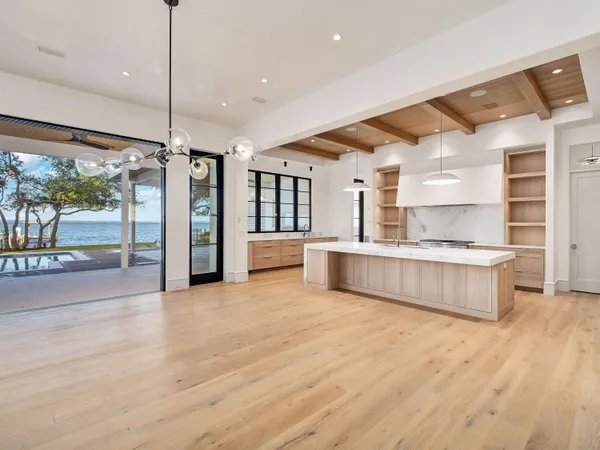 a large kitchen with a large window a counter top space a sink stainless steel appliances and cabinets
