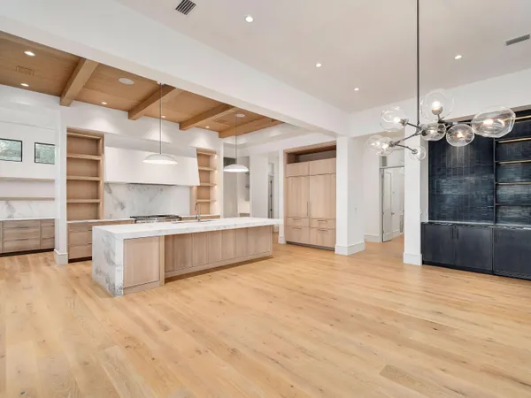 a large kitchen with stainless steel appliances a large counter top a stove and a refrigerator