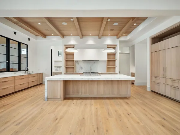 a large kitchen with stainless steel appliances a large counter top a stove and a wooden floors