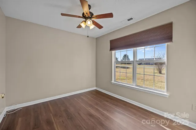 an empty room with a window and a fan