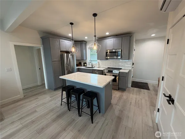 a kitchen with stainless steel appliances granite countertop a sink a stove and a wooden floors