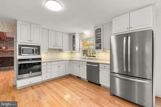 a kitchen with granite countertop stainless steel appliances a refrigerator cabinets and wooden floor