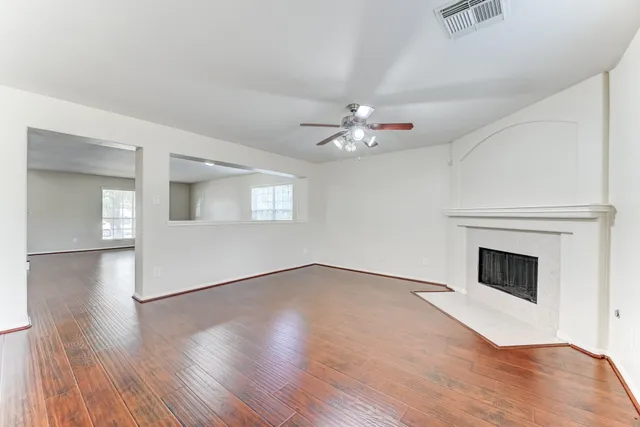 a view of an empty room with wooden floor and a fireplace