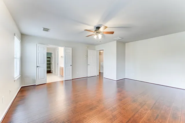 a view of an empty room with window and wooden floor