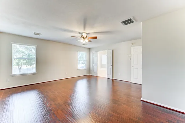 a view of an empty room with a window and wooden floor