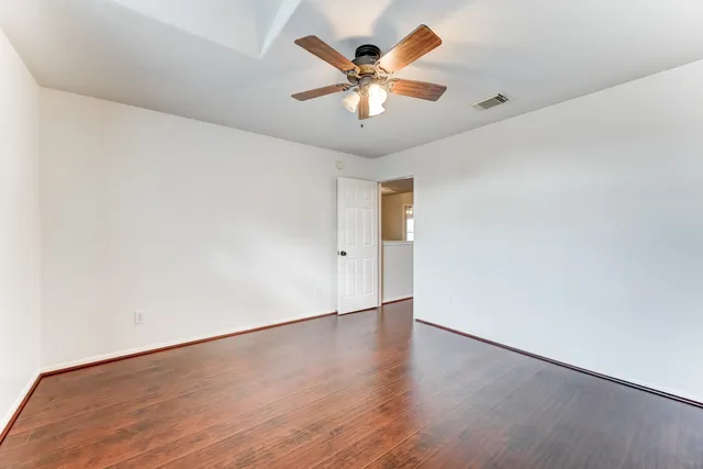 an empty room with wooden floor and ceiling fan