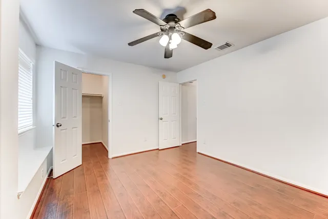 a view of an empty room with window and wooden floor