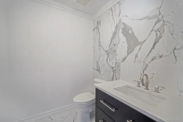 a bathroom with a granite countertop sink a toilet and with a mirror