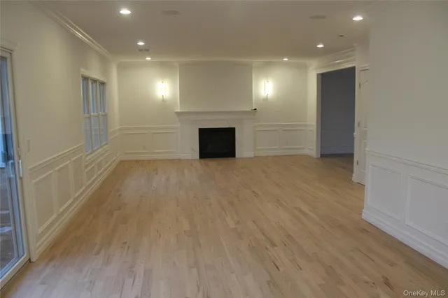 an empty room with wooden floor fireplace and windows