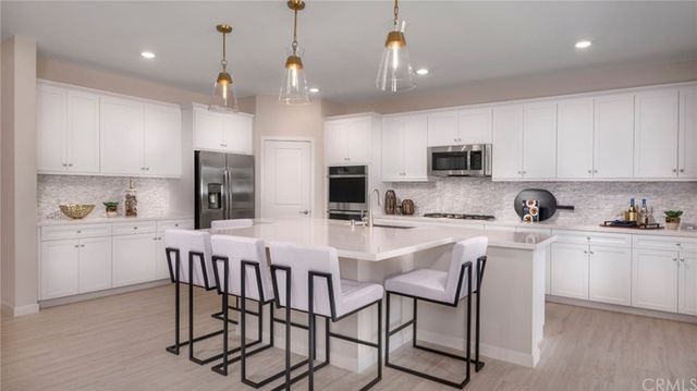 a kitchen with stainless steel appliances kitchen island a table chairs microwave and sink