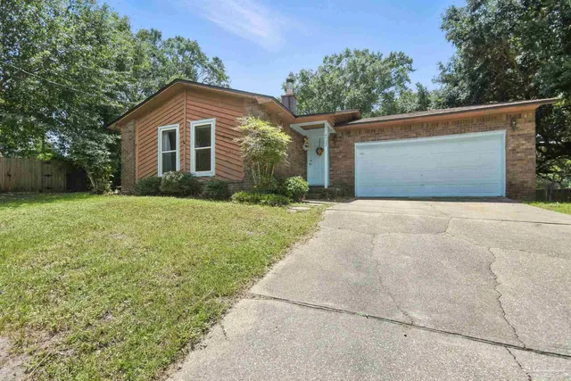 a front view of house with yard and trees in the background