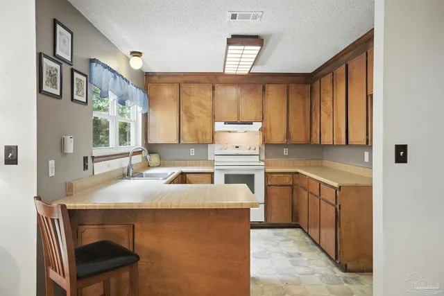 a open kitchen with a stove a sink dishwasher and a refrigerator with wooden cabinets
