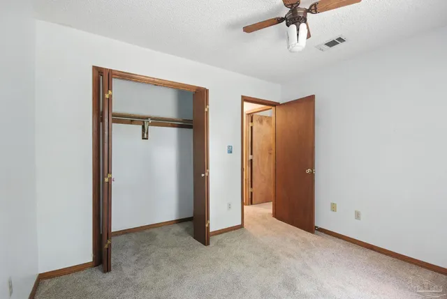 an empty room with windows and ceiling fan