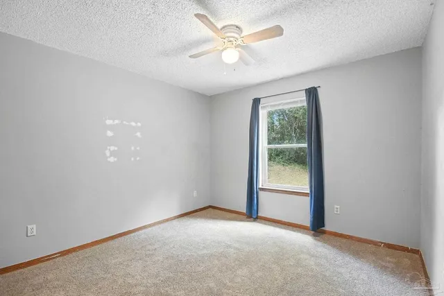 a view of an empty room and chandelier fan