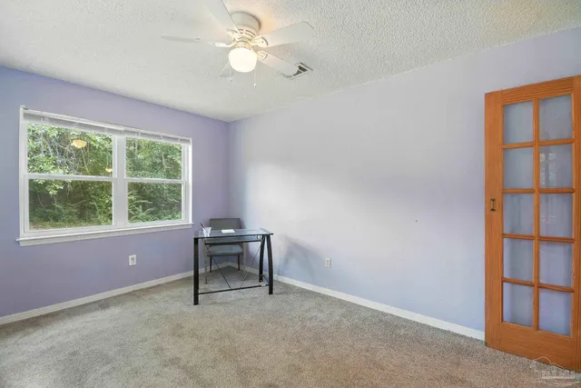 a furnished livingroom with a window and a ceiling fan