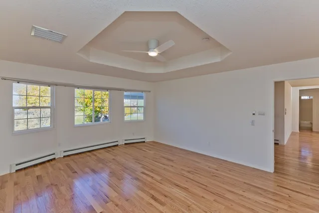 an empty room with wooden floor and windows