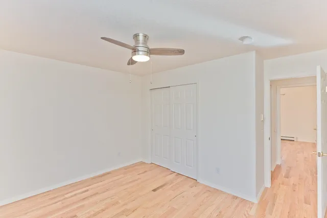 a view of empty room with wooden floor and ceiling fan