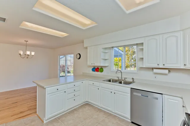 a kitchen with white cabinets a sink dishwasher and a stove with wooden floor