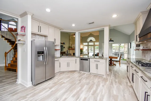 a large white kitchen with stainless steel appliances granite countertop a stove and a sink