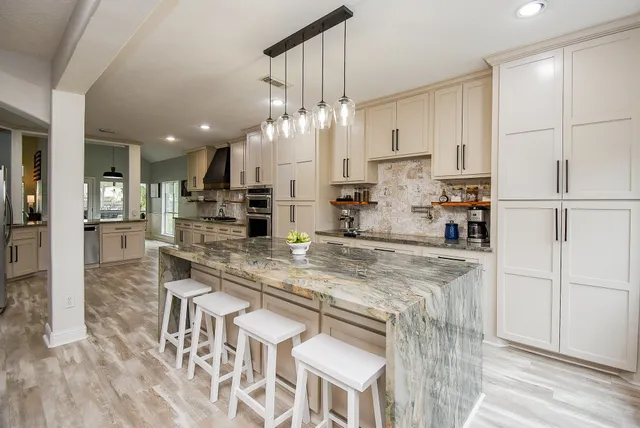 a kitchen with stainless steel appliances granite countertop a white refrigerator a sink dishwasher a dining table and chairs with wooden floor