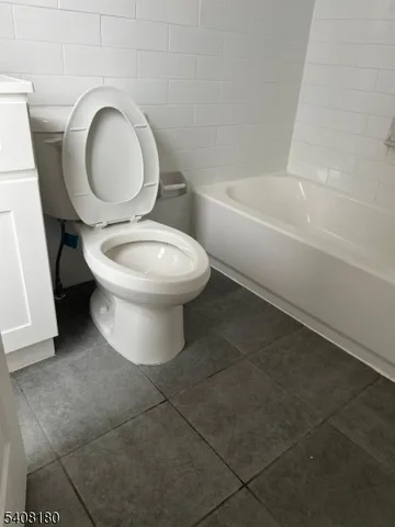 a white toilet sitting next to a bath tub