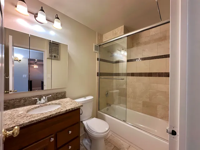 a bathroom with a granite countertop sink toilet and shower