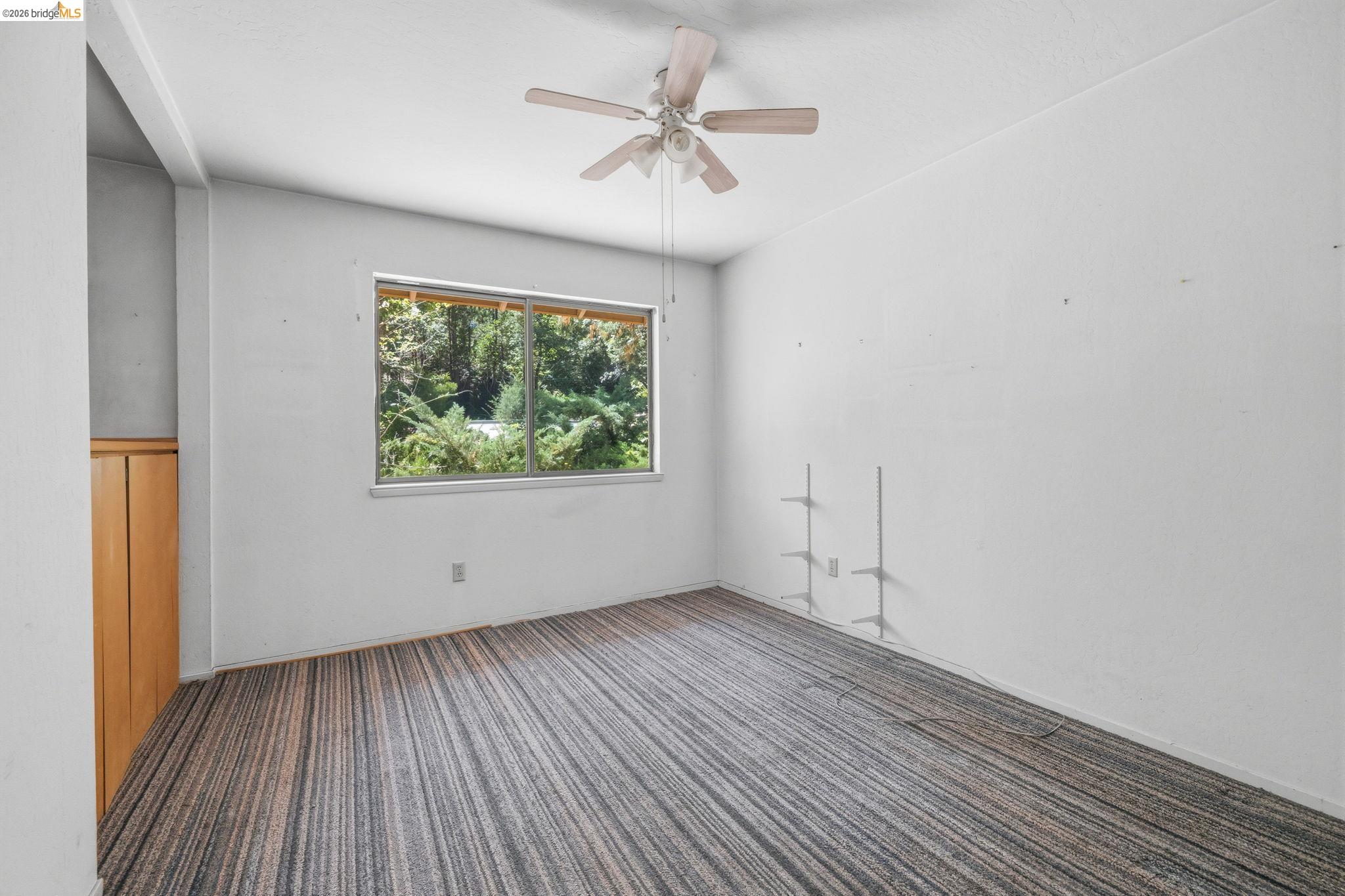 22401 South Fork Road Sonora, CA 95370 - Photo 20 of 34 Room featuring a large window, textured carpeting, built-in wooden cabinetry, and a ceiling fan
