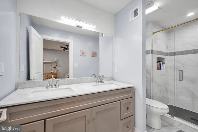 a bathroom with a granite countertop sink a toilet and shower