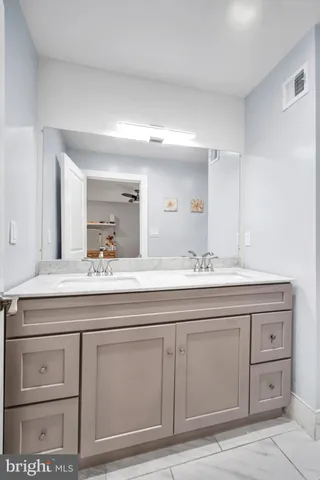 a bathroom with a granite countertop double vanity sink and mirror