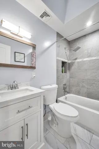 a bathroom with a toilet a sink a mirror a bathtub and vanity