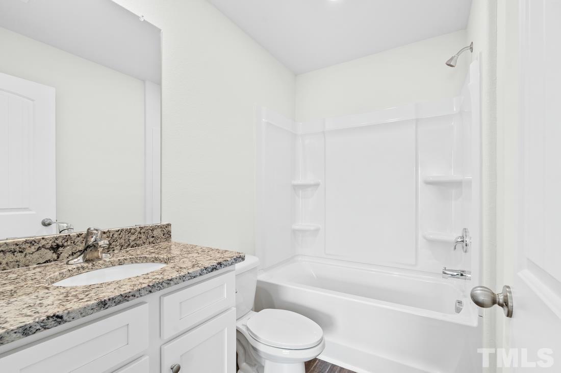 533 Crackling Court Zebulon, NC 27597 - Photo 12 of 14 a bathroom with a granite countertop sink a toilet and bathtub