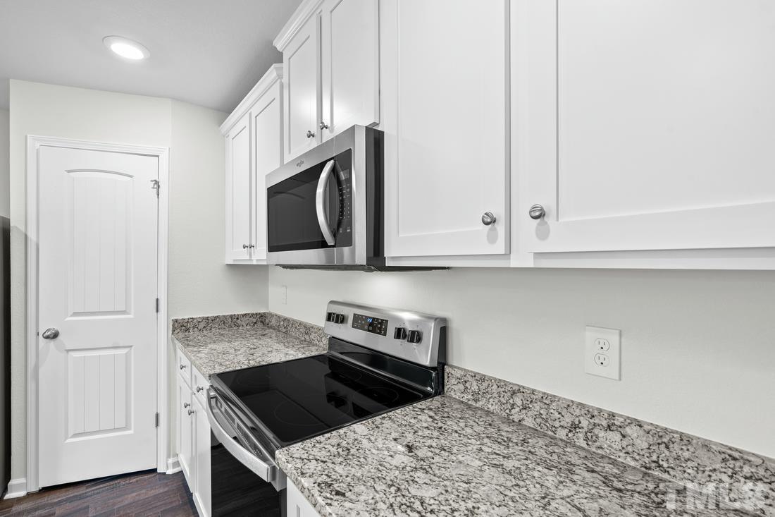 533 Crackling Court Zebulon, NC 27597 - Photo 4 of 14 a kitchen with granite countertop white cabinets and stainless steel appliances