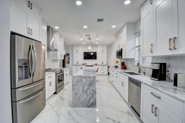 a large kitchen with stainless steel appliances refrigerator a microwave and cabinets