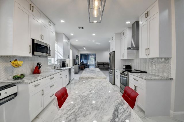 a kitchen with stainless steel appliances kitchen island granite countertop a sink stove and refrigerator