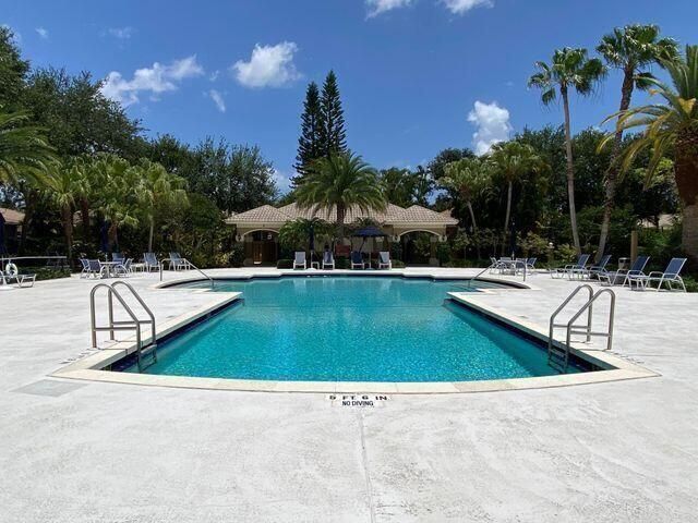 a view of swimming pool with outdoor seating and trees in the background