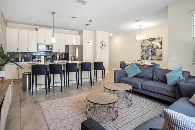 a living room with furniture a table and kitchen view