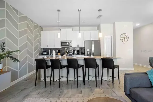 a kitchen with stainless steel appliances kitchen island granite countertop a table chairs and a living room