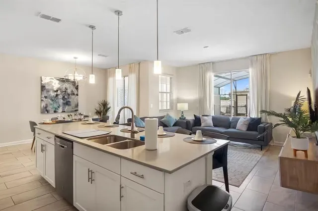 a kitchen with stainless steel appliances granite countertop a sink a counter space and living room view