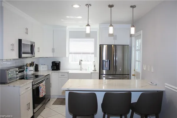 a kitchen with stainless steel appliances granite countertop a sink a stove a refrigerator and island with wooden floor