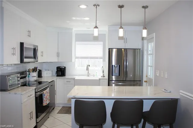 a kitchen with stainless steel appliances granite countertop a sink a stove a refrigerator and island with wooden floor